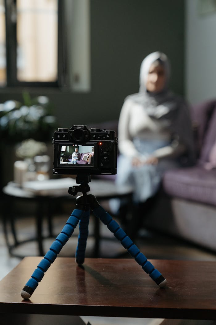 about-us Camera on a tripod filming a woman in a cozy living room setting for a vlog.